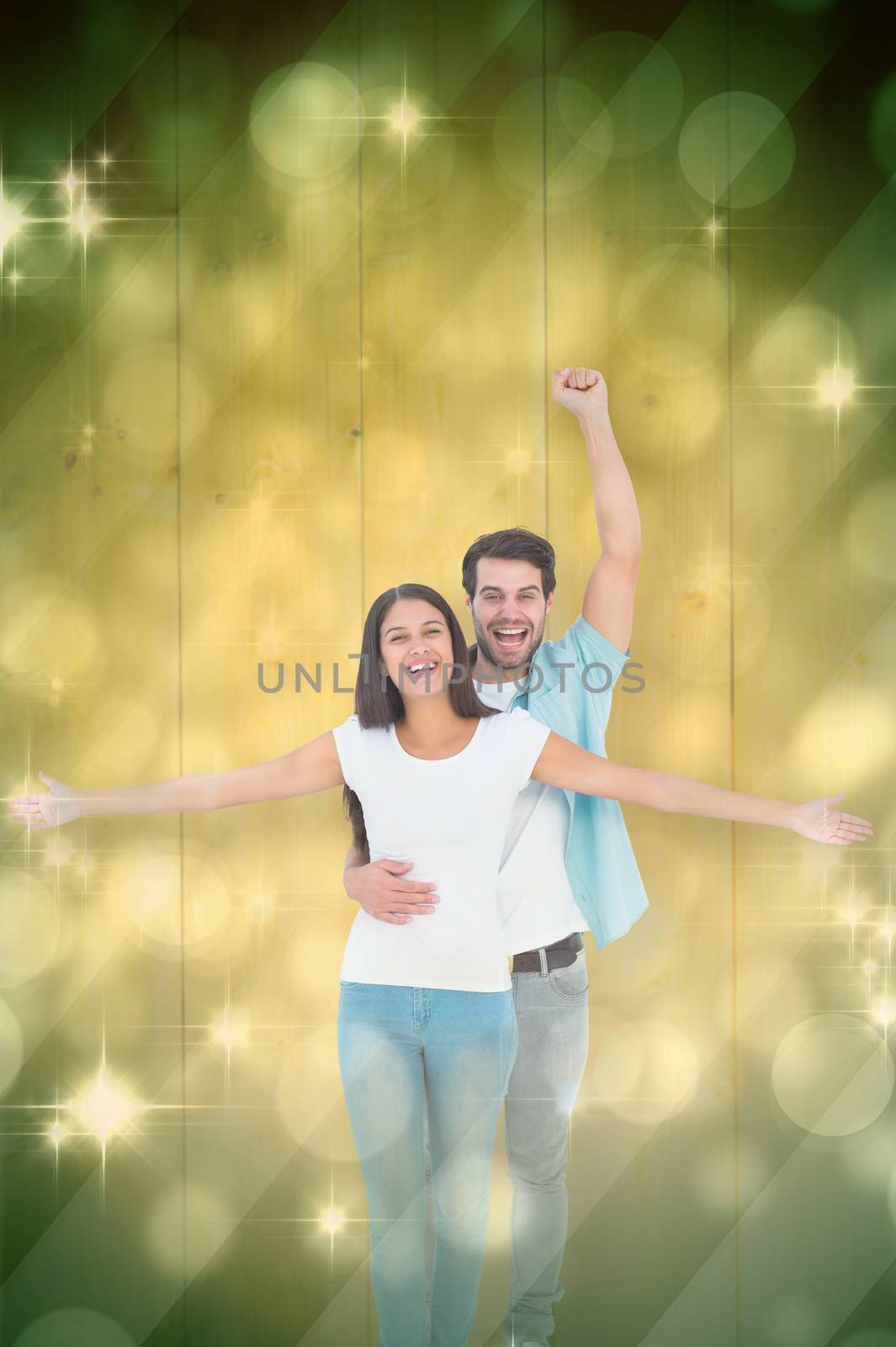 Happy casual couple cheering together against light design shimmering on green
