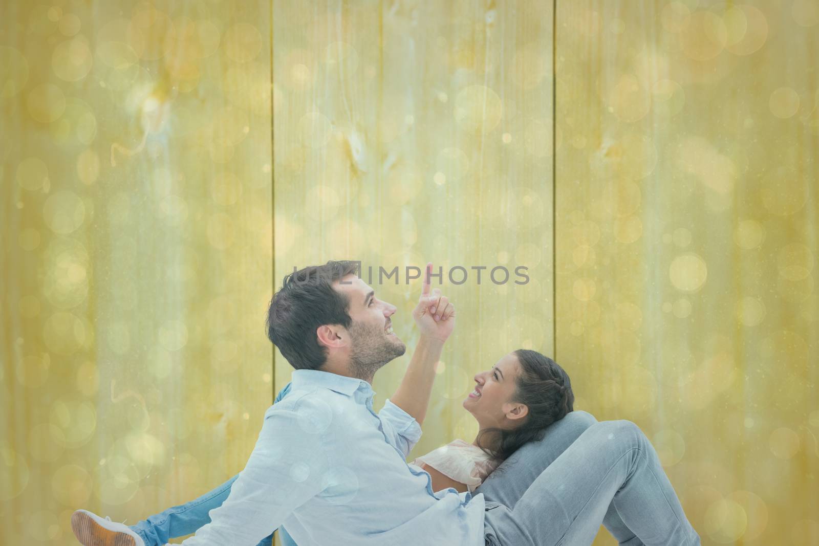 Attractive young couple lying down against blue abstract light spot design