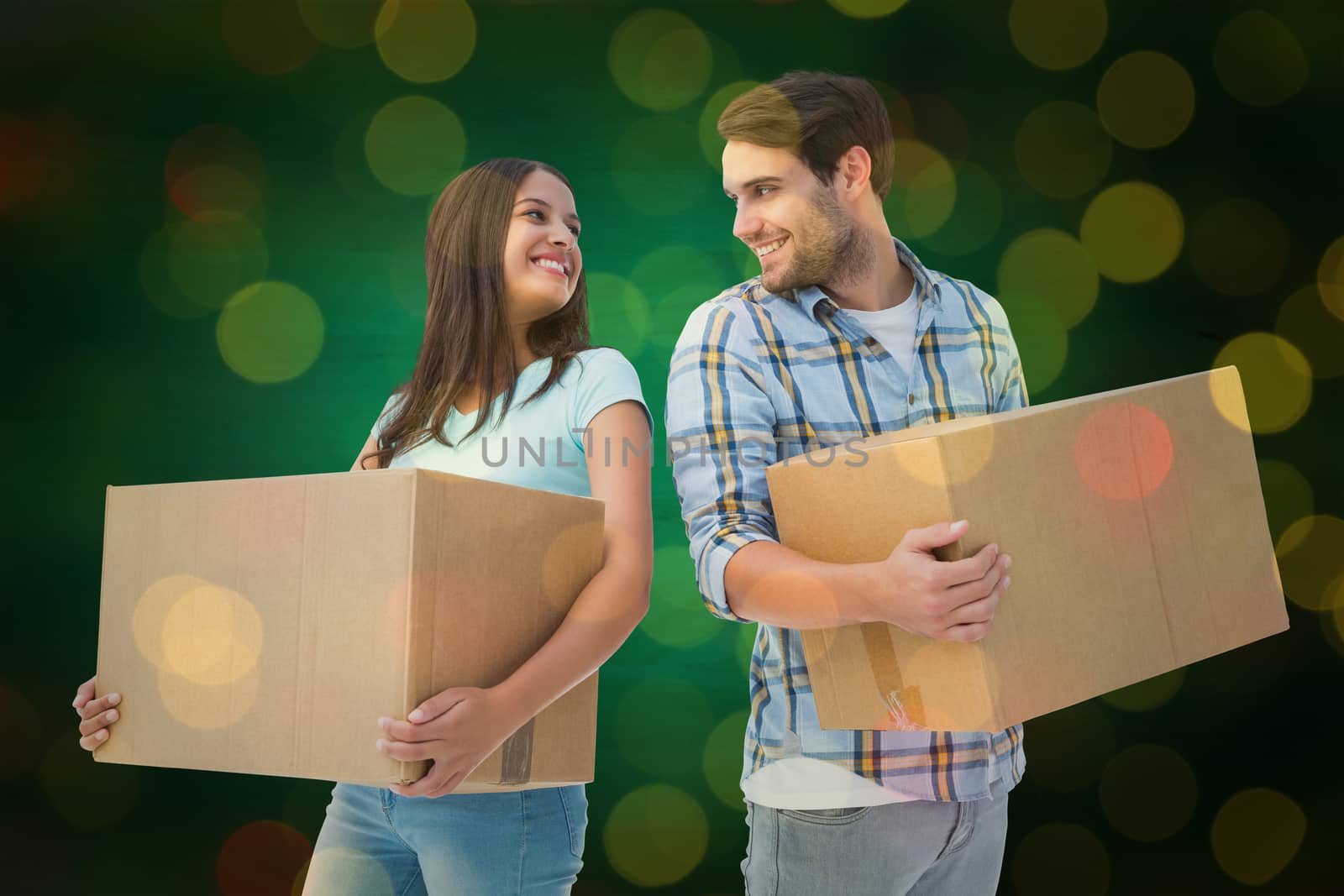 Happy young couple with moving boxes against close up of christmas lights