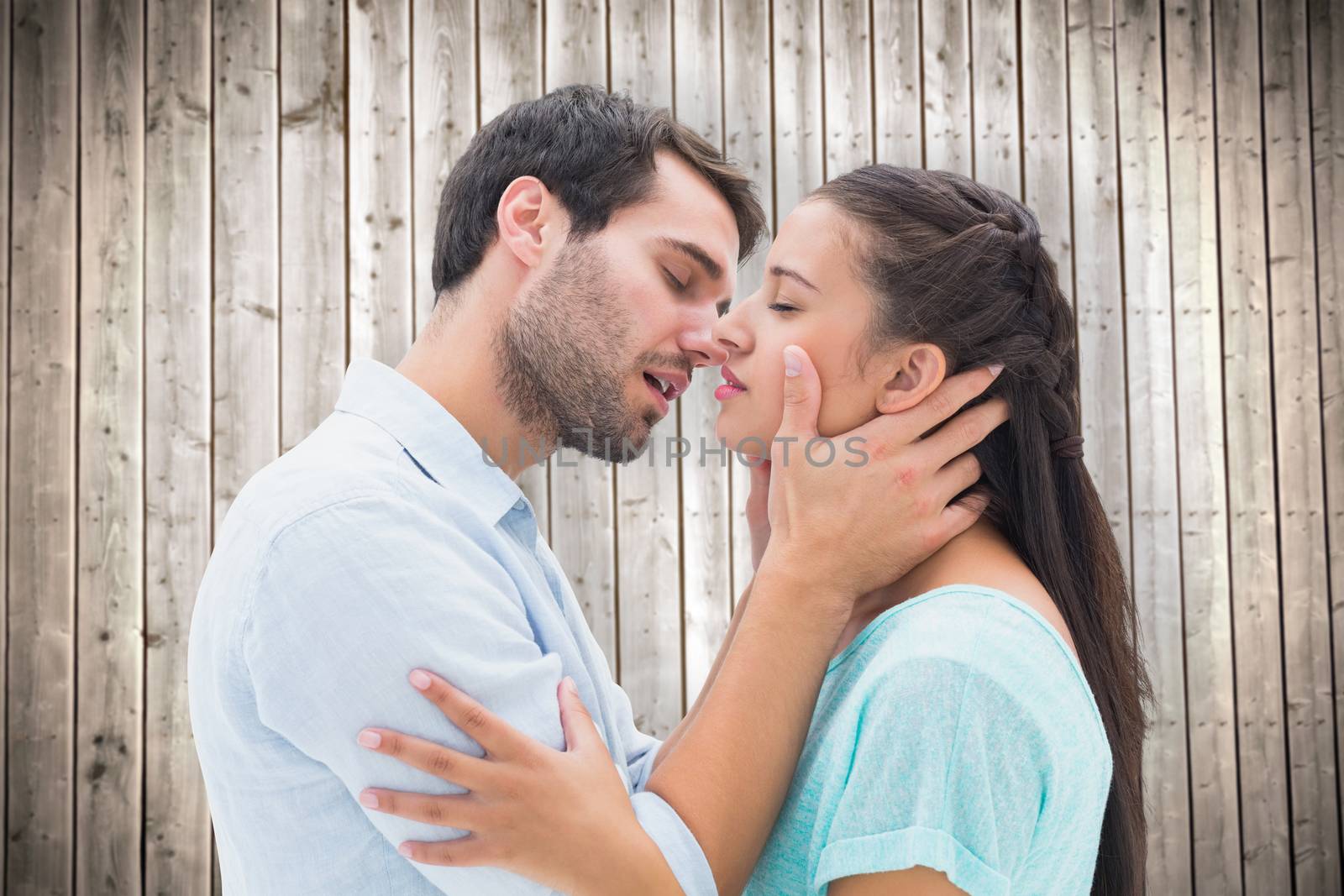 Attractive young couple about to kiss against wooden planks background