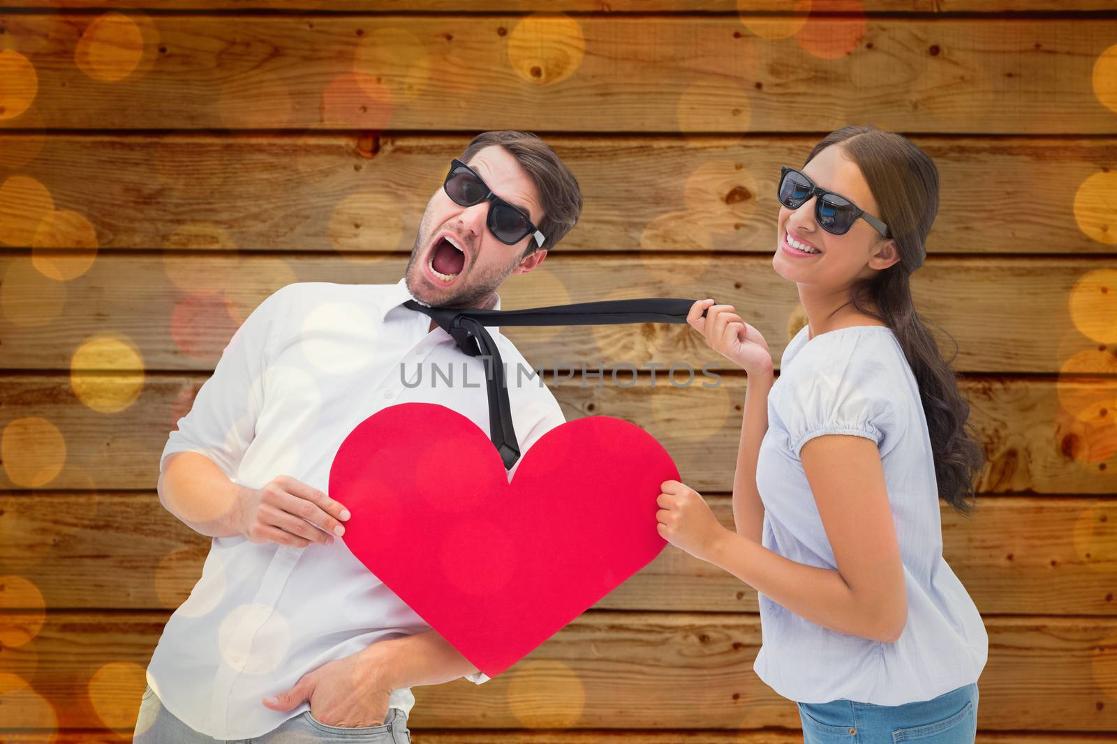 Composite image of brunette pulling her boyfriend by the tie holding heart by Wavebreakmedia