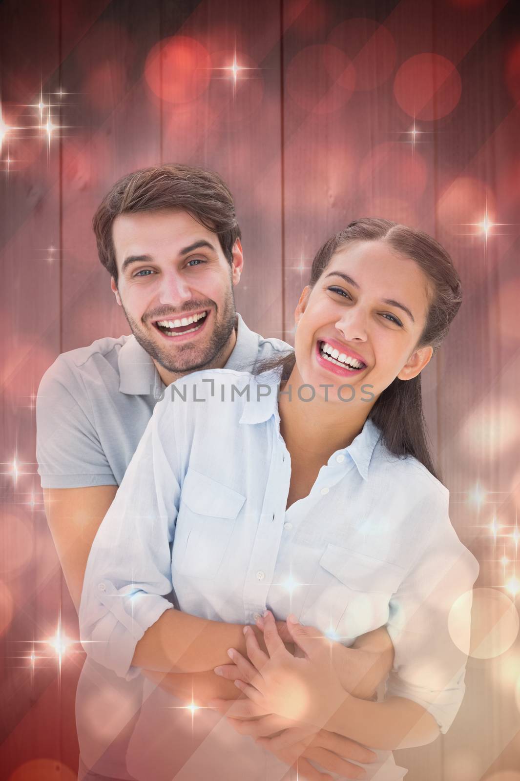 Cute couple hugging and smiling at camera against light design shimmering on red