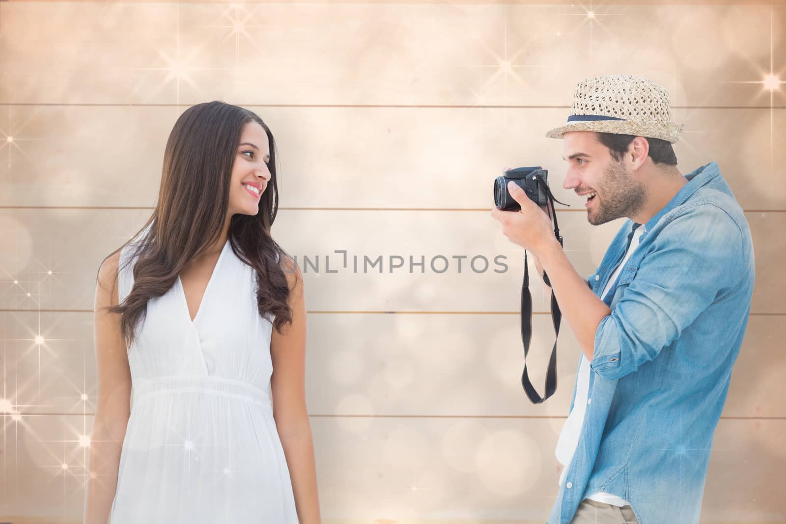 Handsome hipster taking a photo of pretty girlfriend against shimmering light design on grey