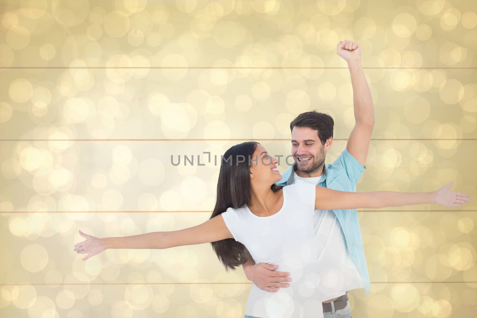 Happy casual couple cheering together against light glowing dots design pattern