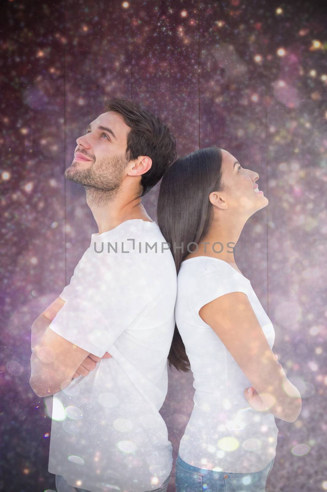 Happy couple standing looking up against white snow and stars on black