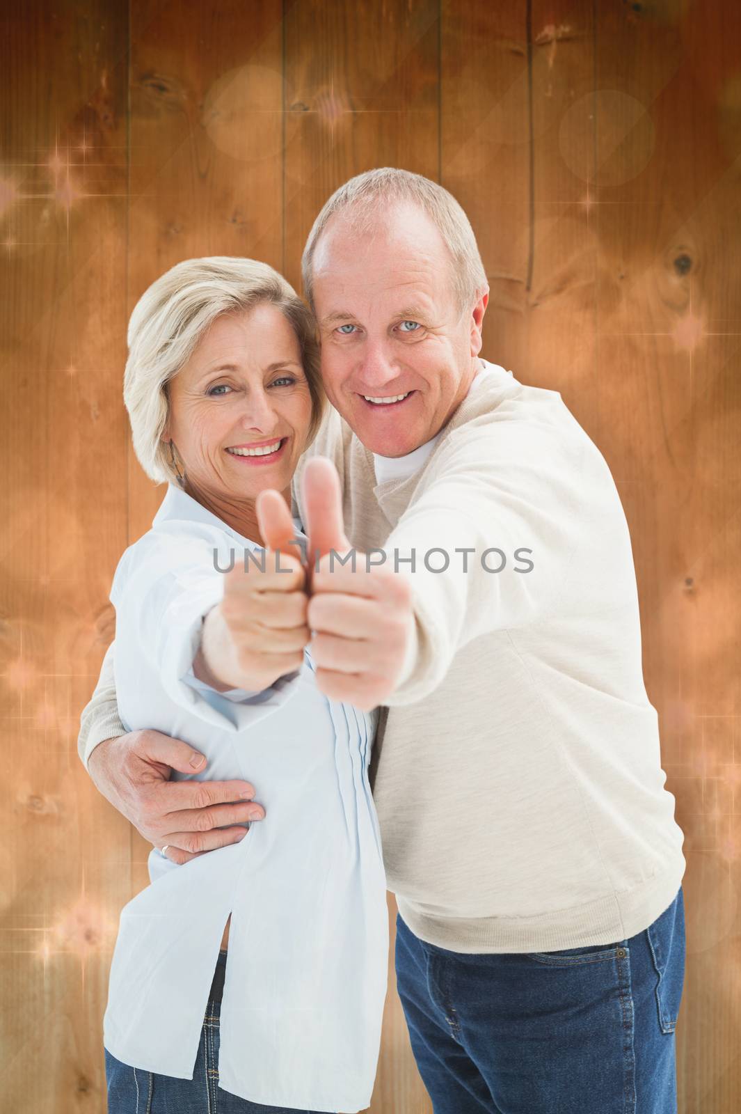 Happy mature couple showing thumbs up against light design shimmering on green
