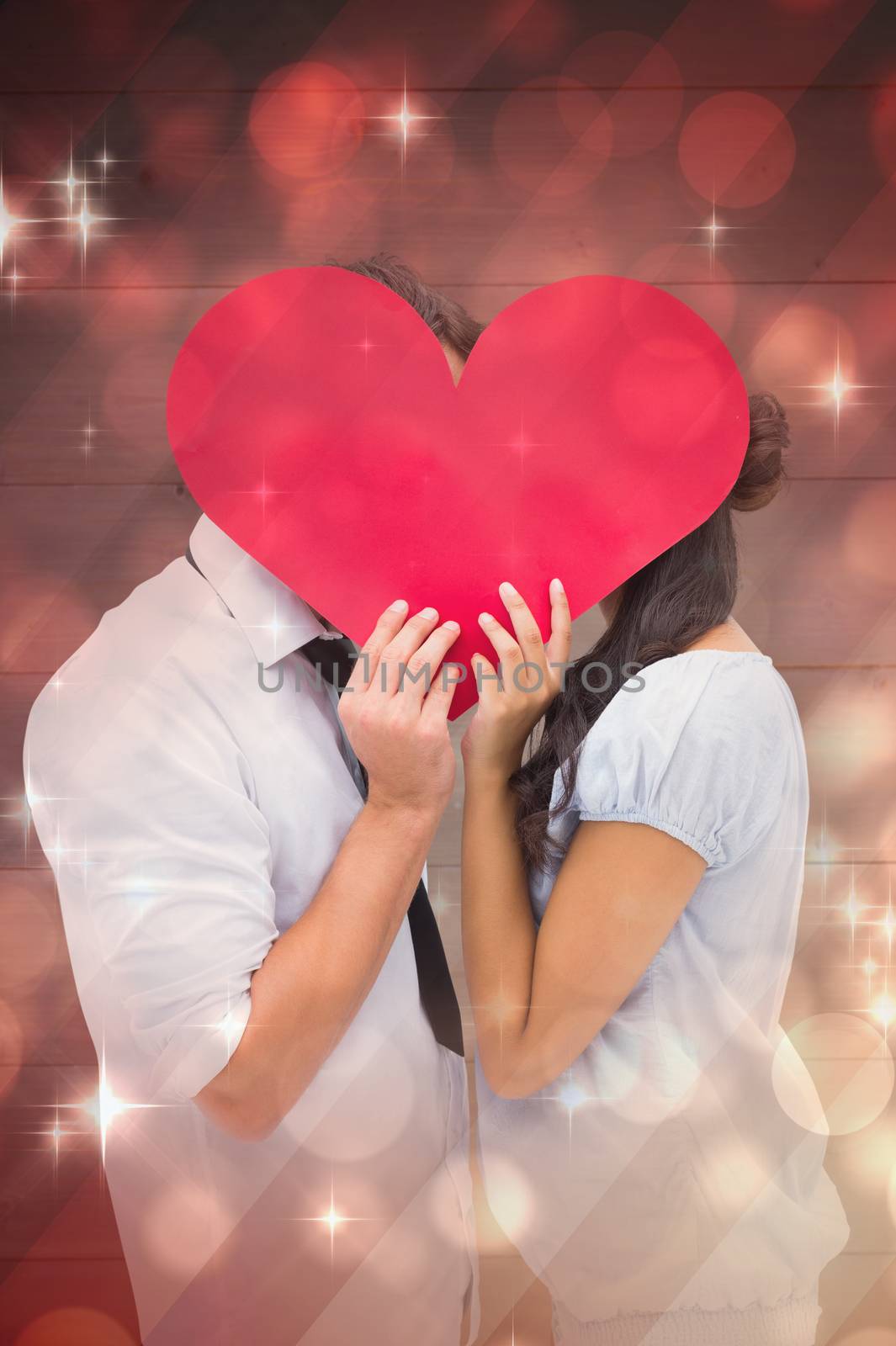 Composite image of couple covering their kiss with a heart by Wavebreakmedia