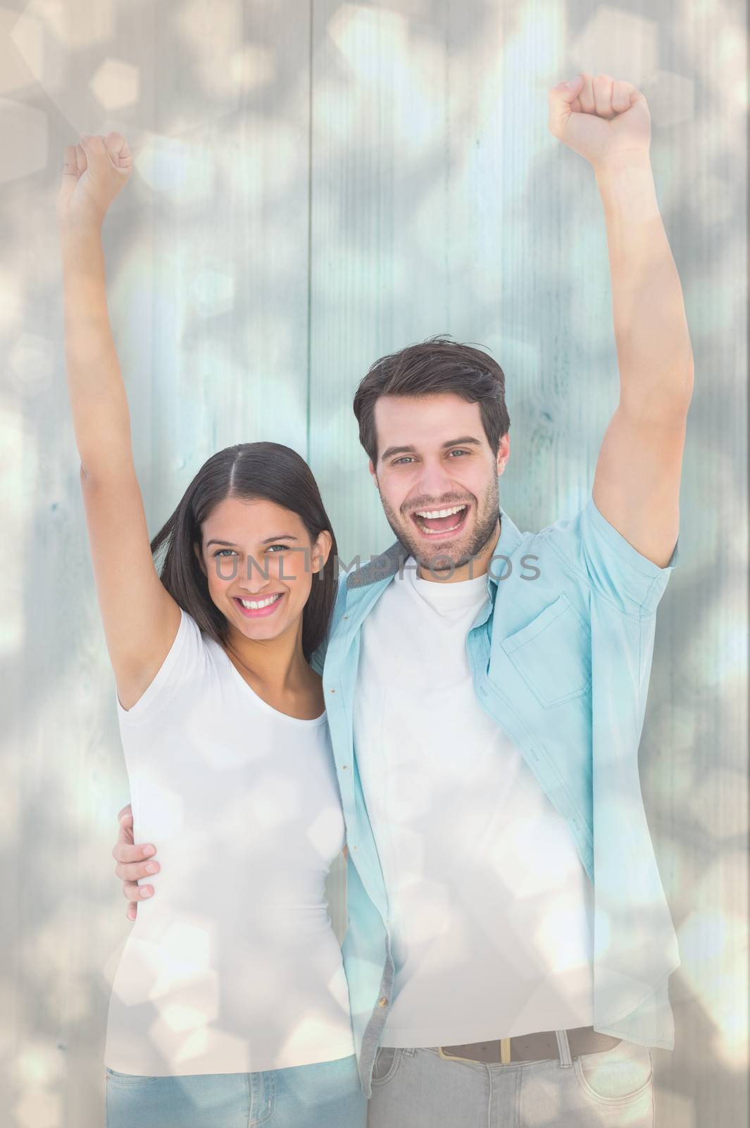 Happy casual couple cheering together against light glowing dots design pattern