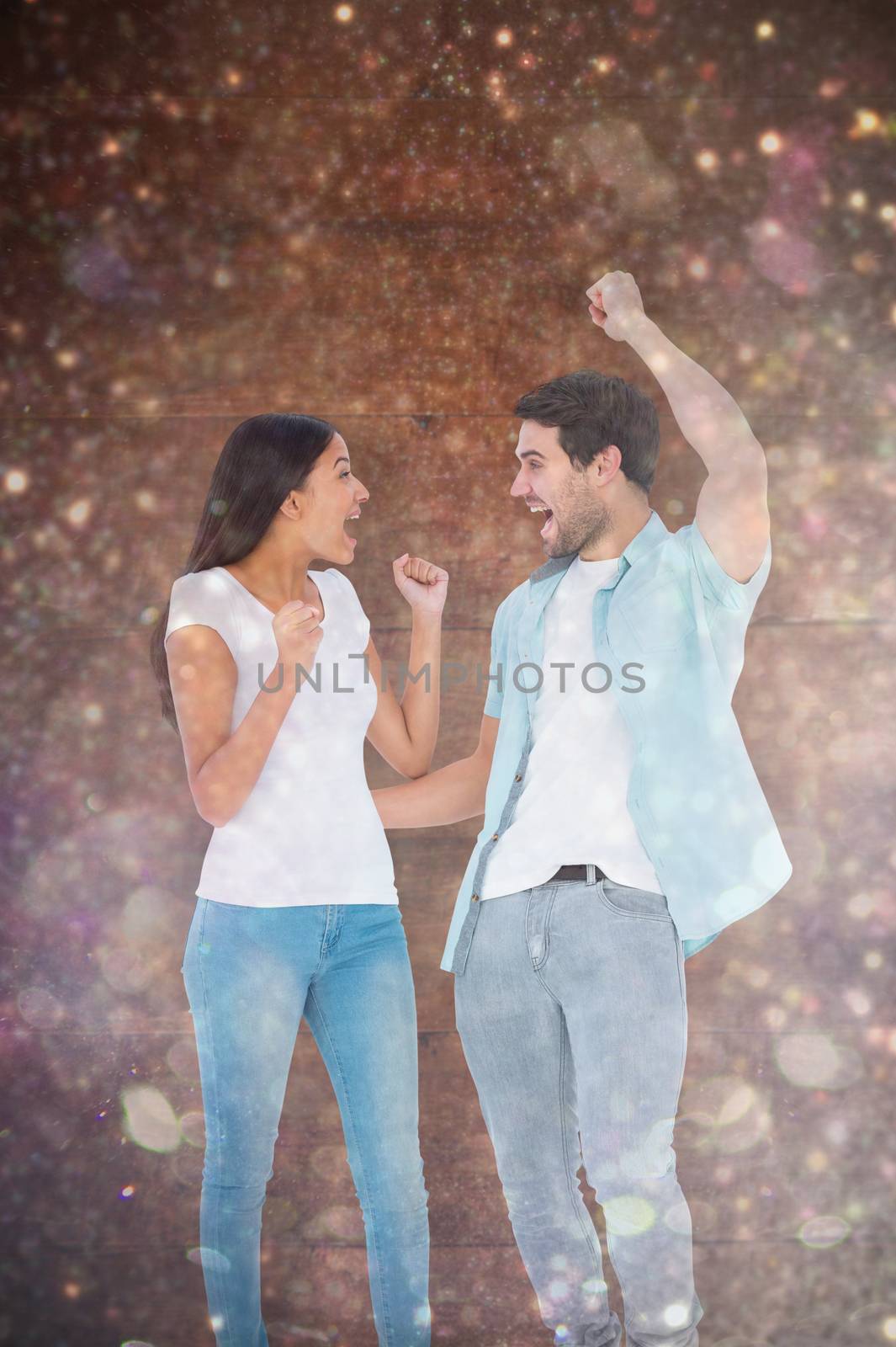 Composite image of happy casual couple cheering together by Wavebreakmedia