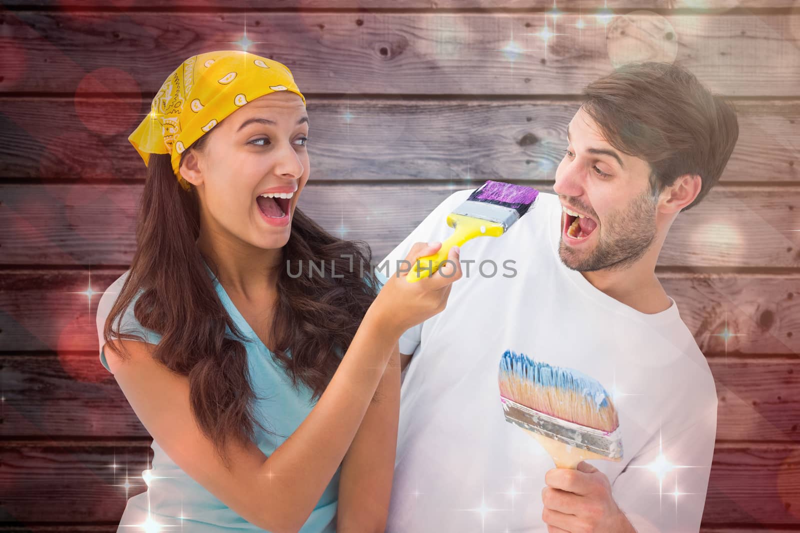 Happy young couple painting together and laughing against light design shimmering on red