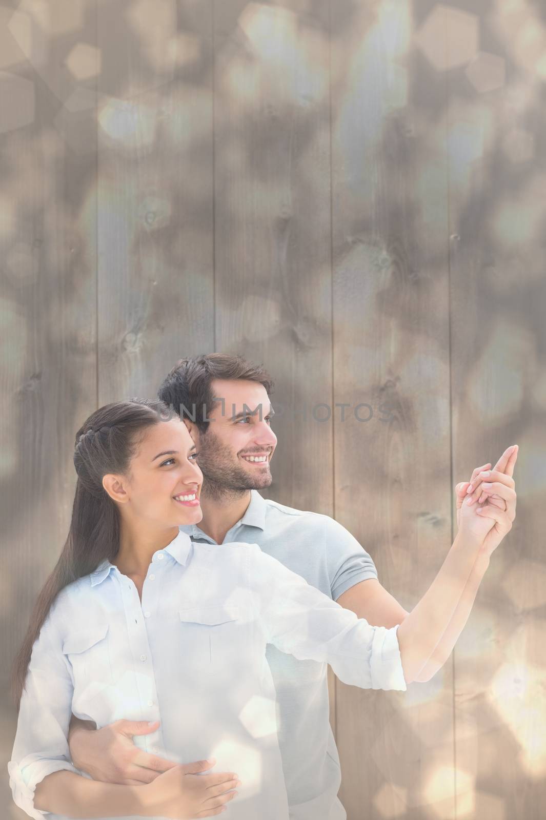 Composite image of cute couple embracing and pointing by Wavebreakmedia