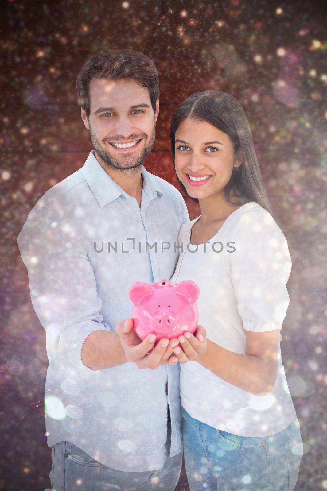 Composite image of happy couple showing their piggy bank by Wavebreakmedia