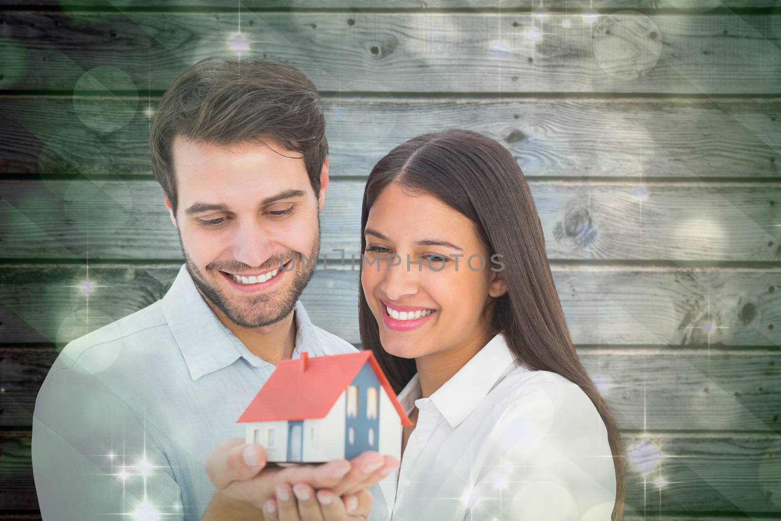 Composite image of attractive young couple holding a model house by Wavebreakmedia