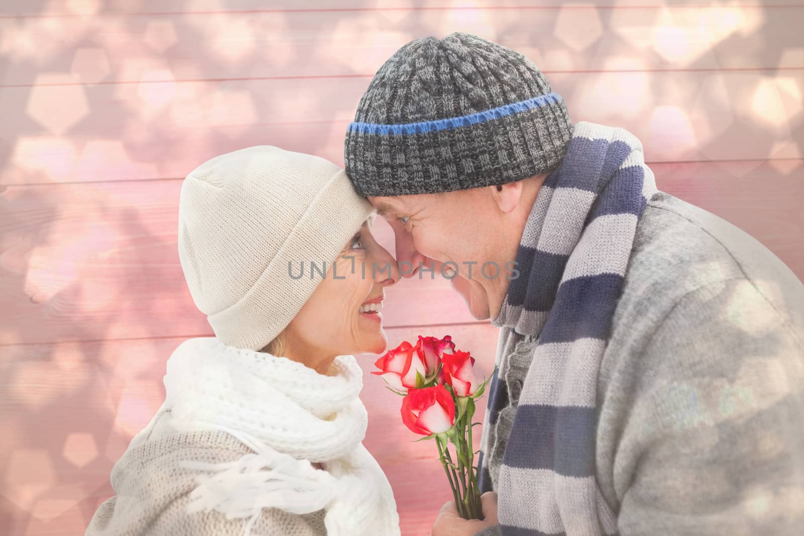 Happy mature couple in winter clothes with roses against light glowing dots design pattern