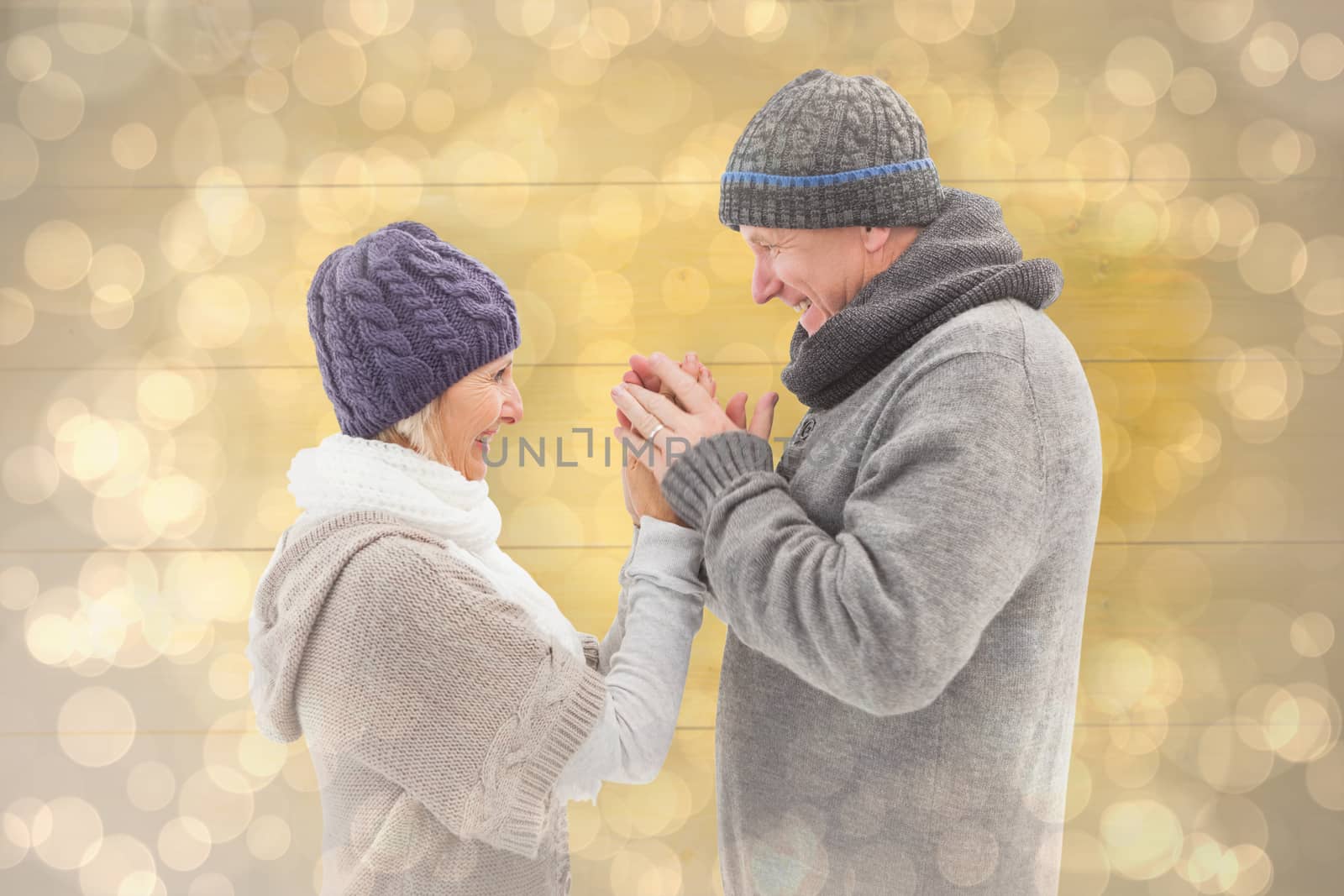 Happy mature couple in winter clothes embracing against light glowing dots design pattern