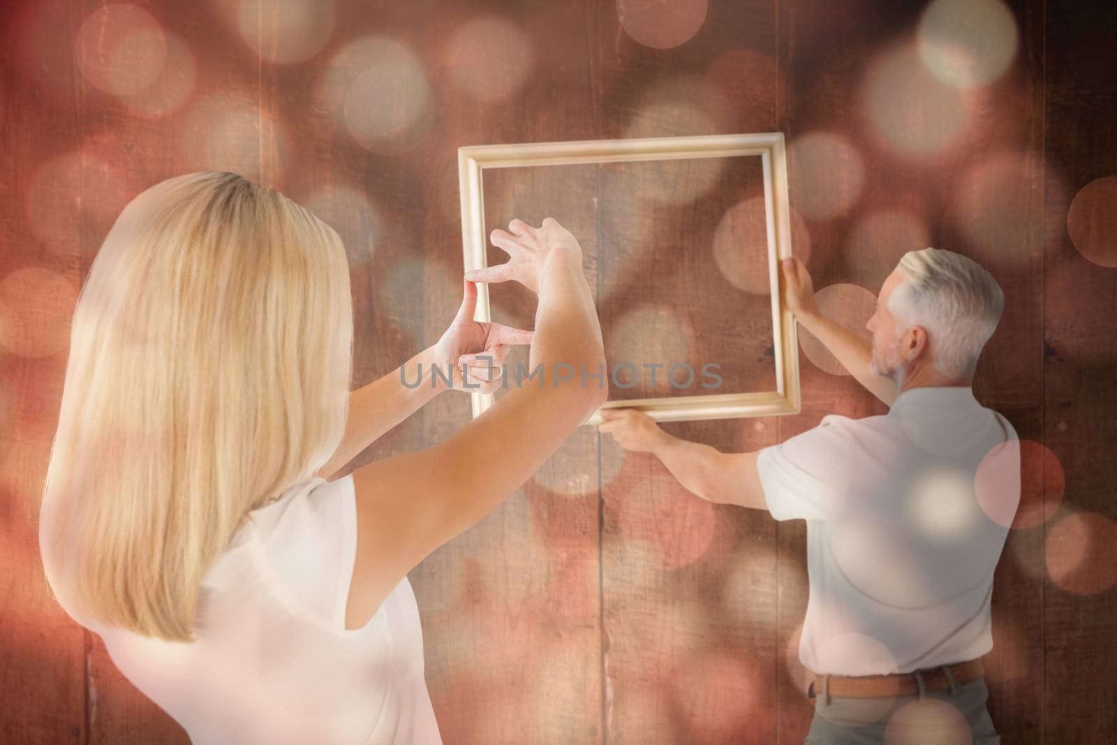 Couple hanging a frame together against light circles on black background