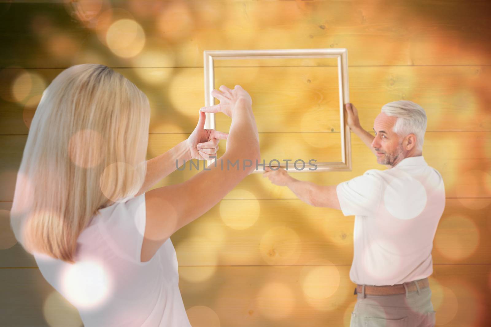 Couple hanging a frame together against light circles on black background