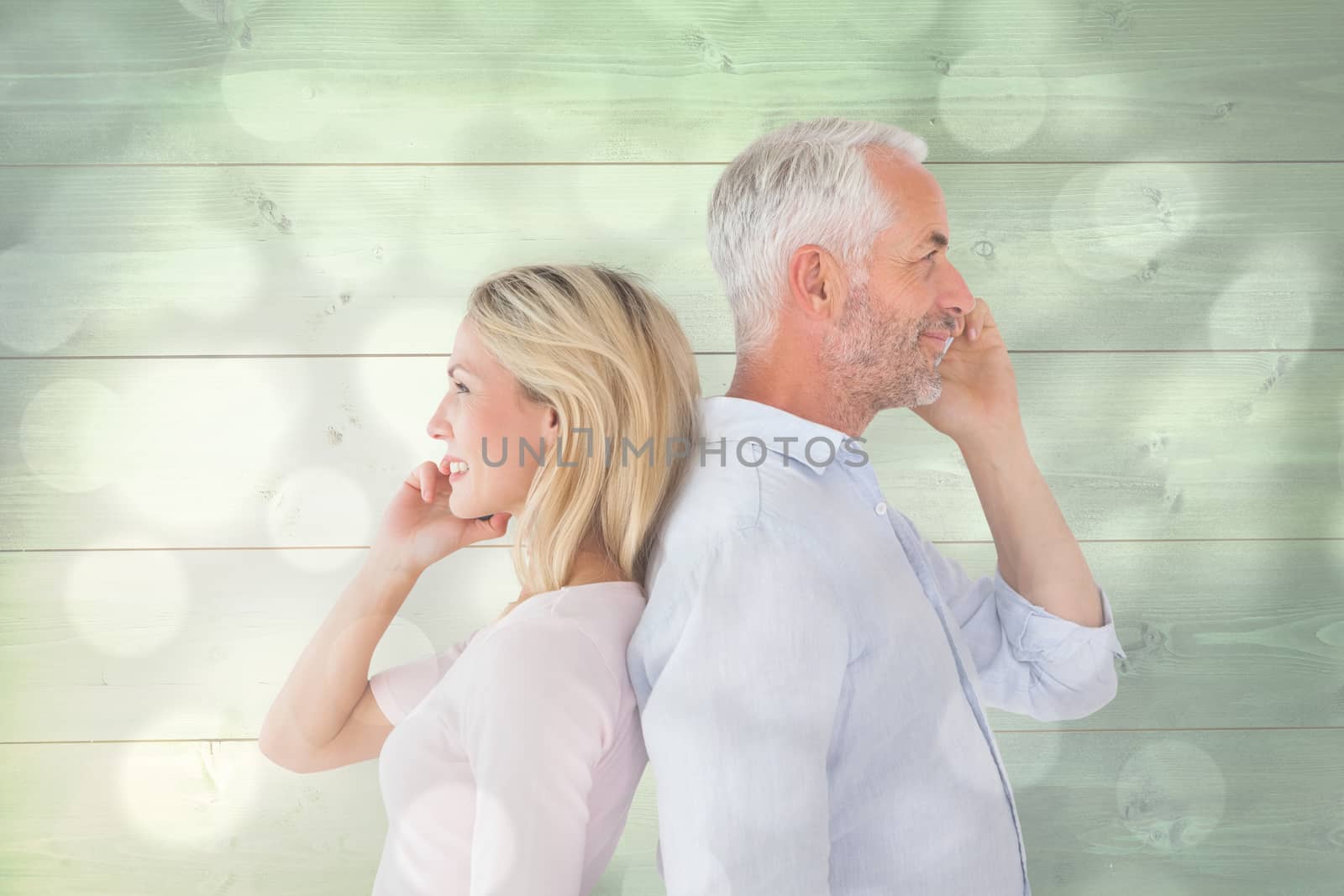 Happy couple talking on their smartphones against light circles on grey background