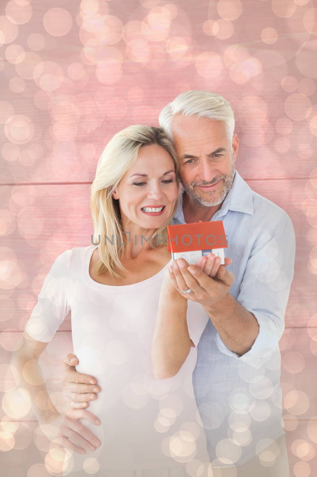 Composite image of happy couple holding miniature model house by Wavebreakmedia