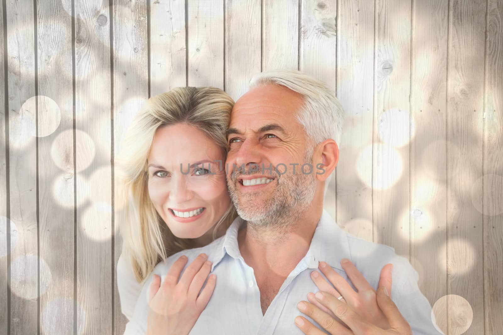 Smiling couple embracing with woman looking at camera against light circles on bright background