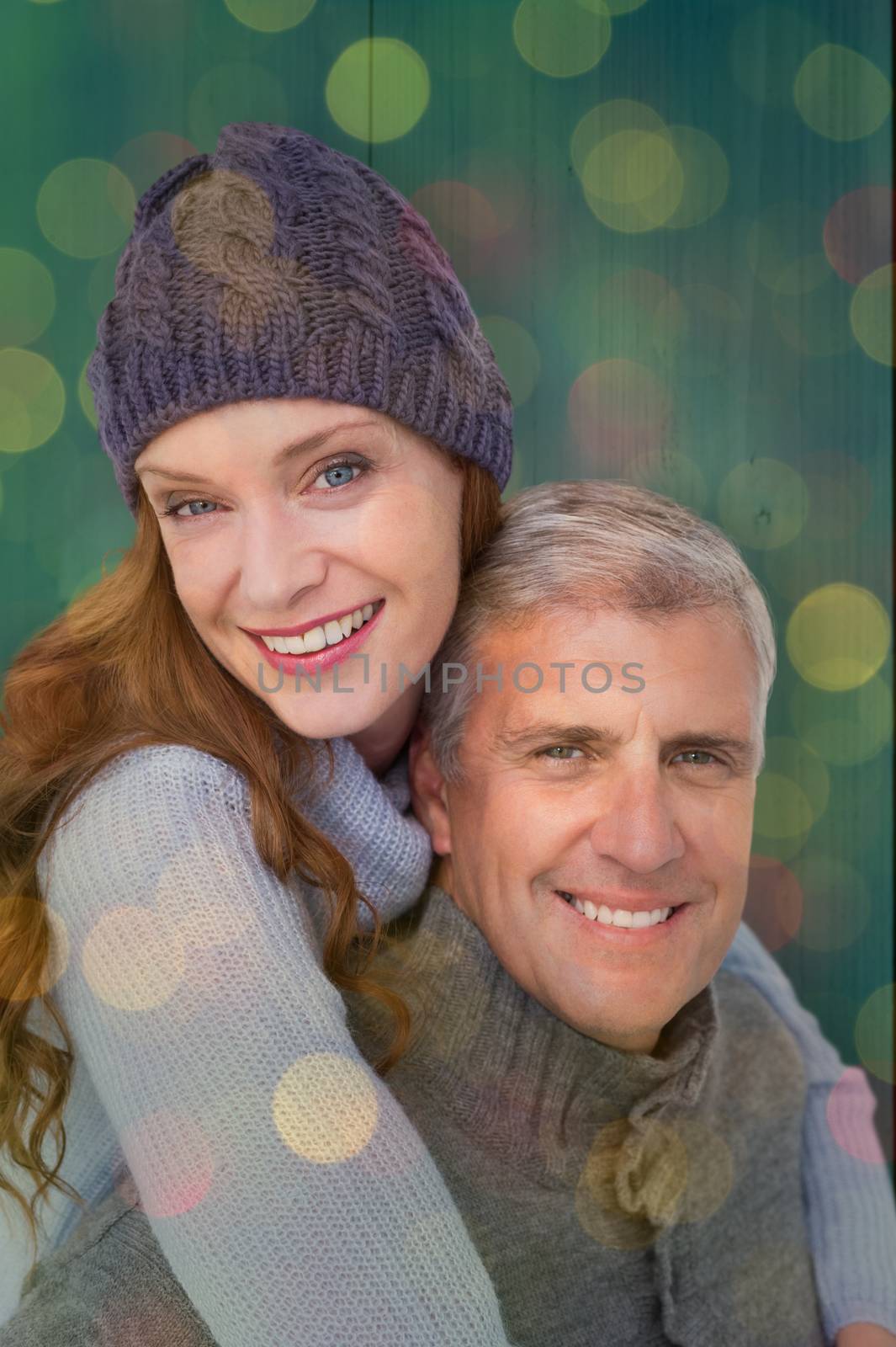 Happy couple in warm clothing against close up of christmas lights