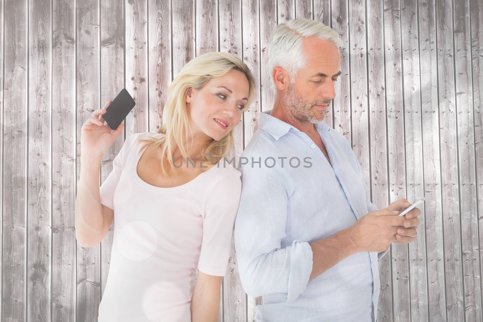 Happy couple texting on their smartphones against light circles on grey background