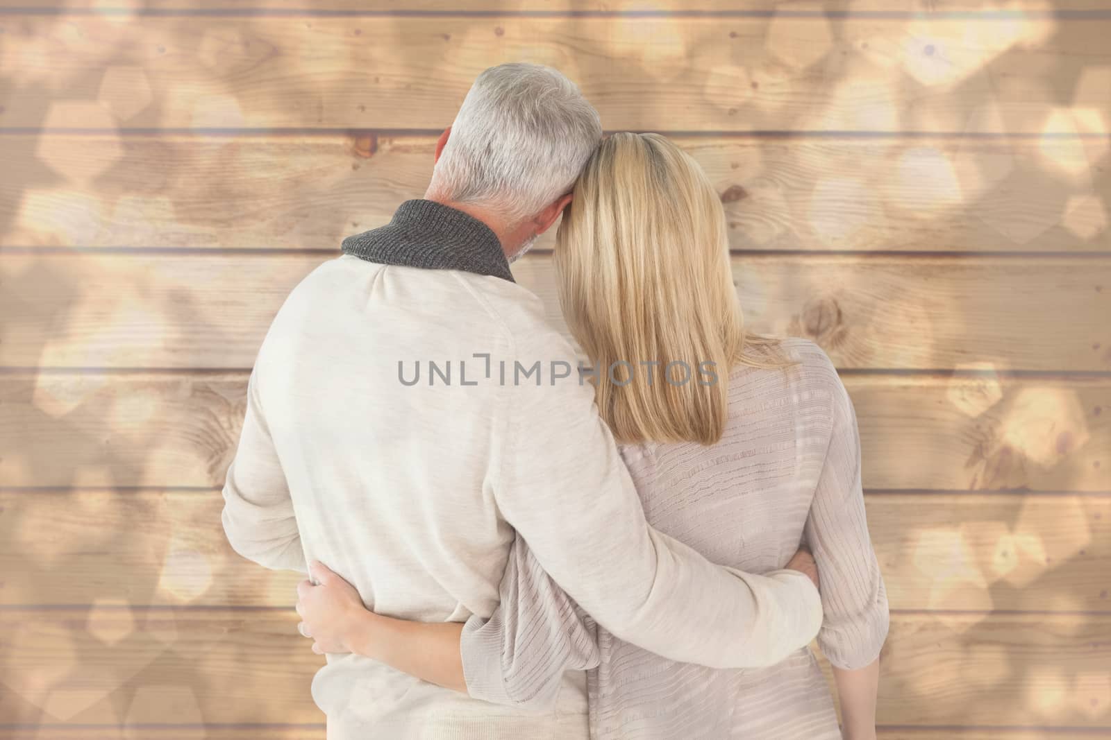 Happy couple standing with arms around against light glowing dots design pattern
