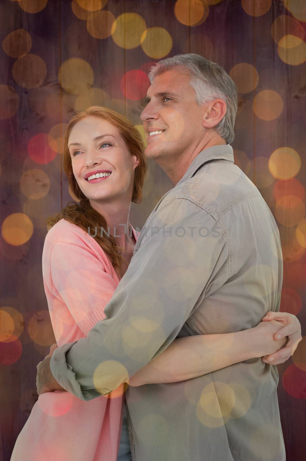 Casual couple hugging and smiling against close up of christmas lights