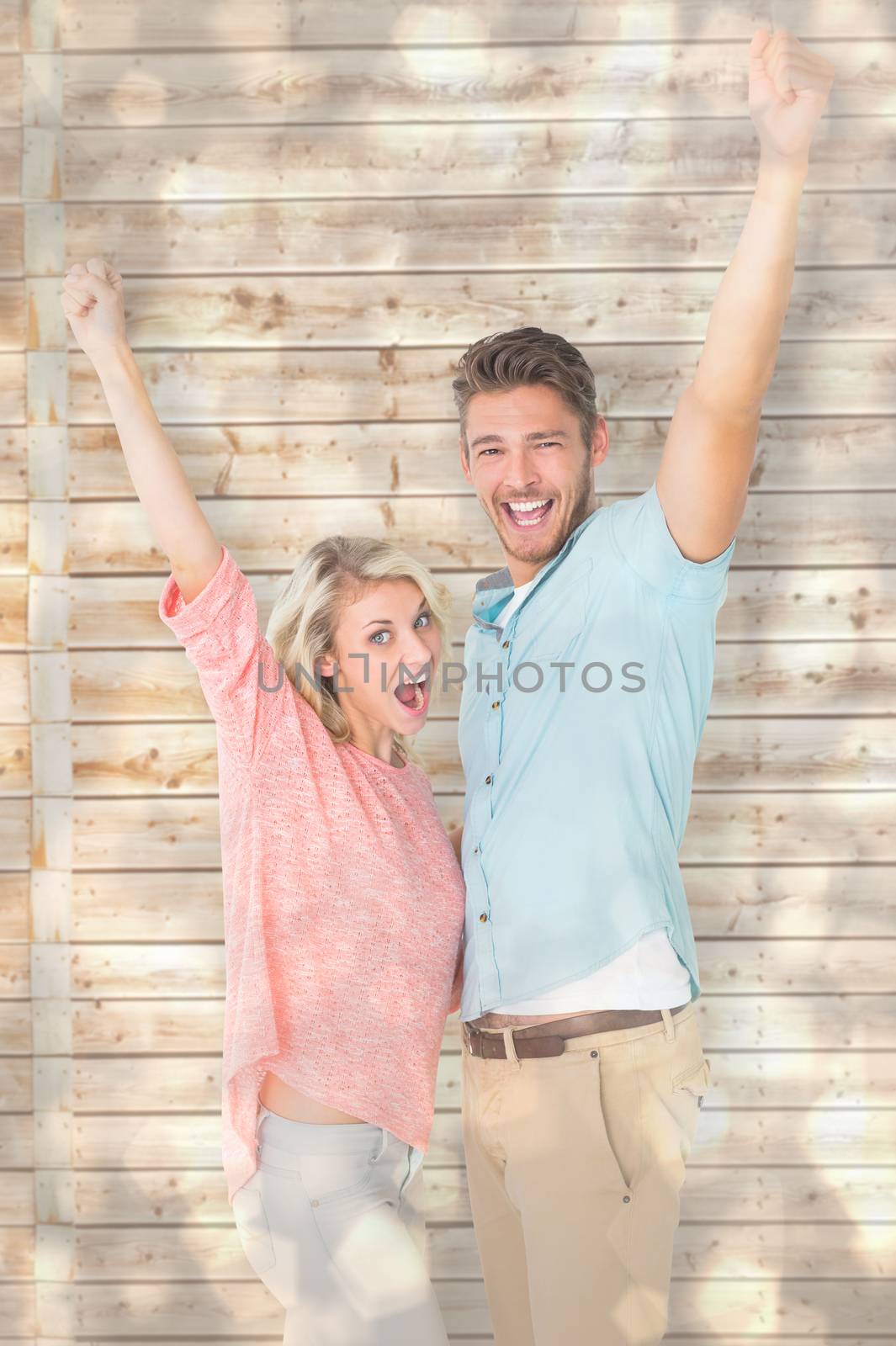 Attractive couple smiling and cheering against light glowing dots design pattern