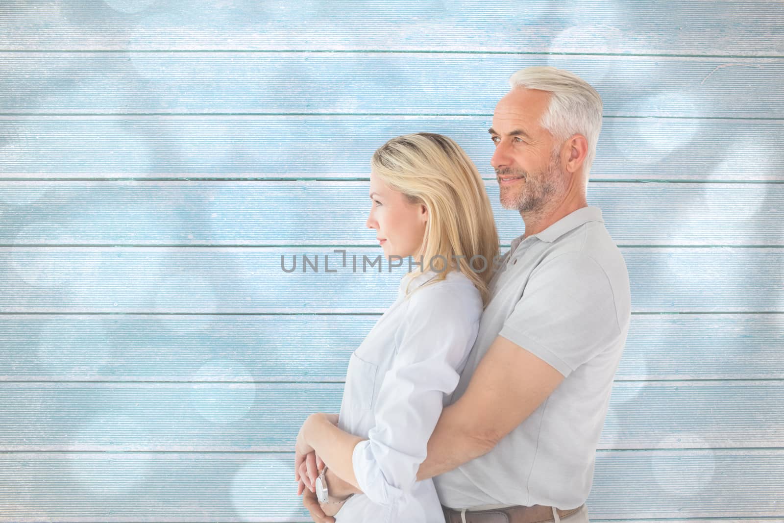Happy couple smiling and embracing against light circles on grey background