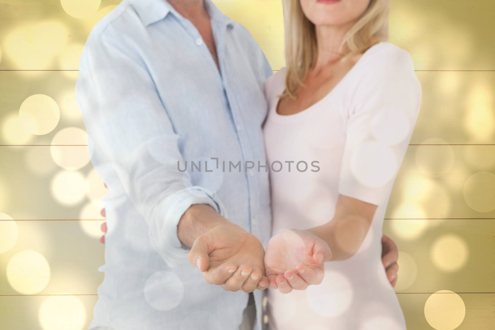 Happy couple holding their hands out against light circles on bright background