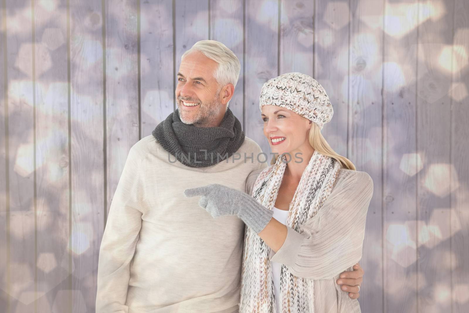 Happy couple in winter fashion looking against light glowing dots design pattern