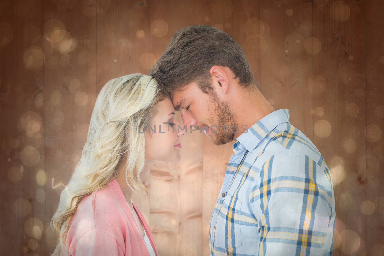 Attractive couple standing touching heads against black abstract light spot design