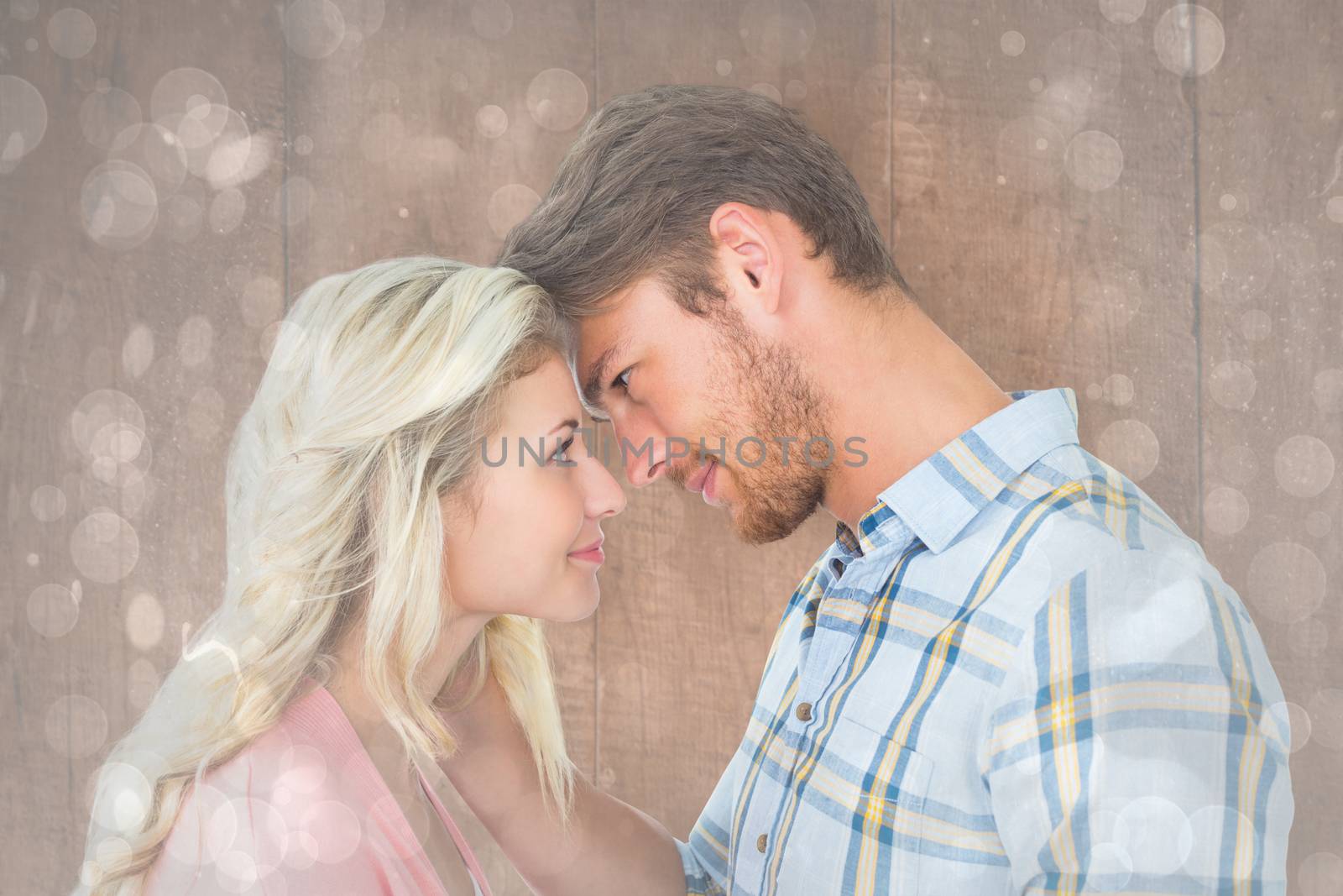 Attractive couple smiling at each other against grey abstract light spot design