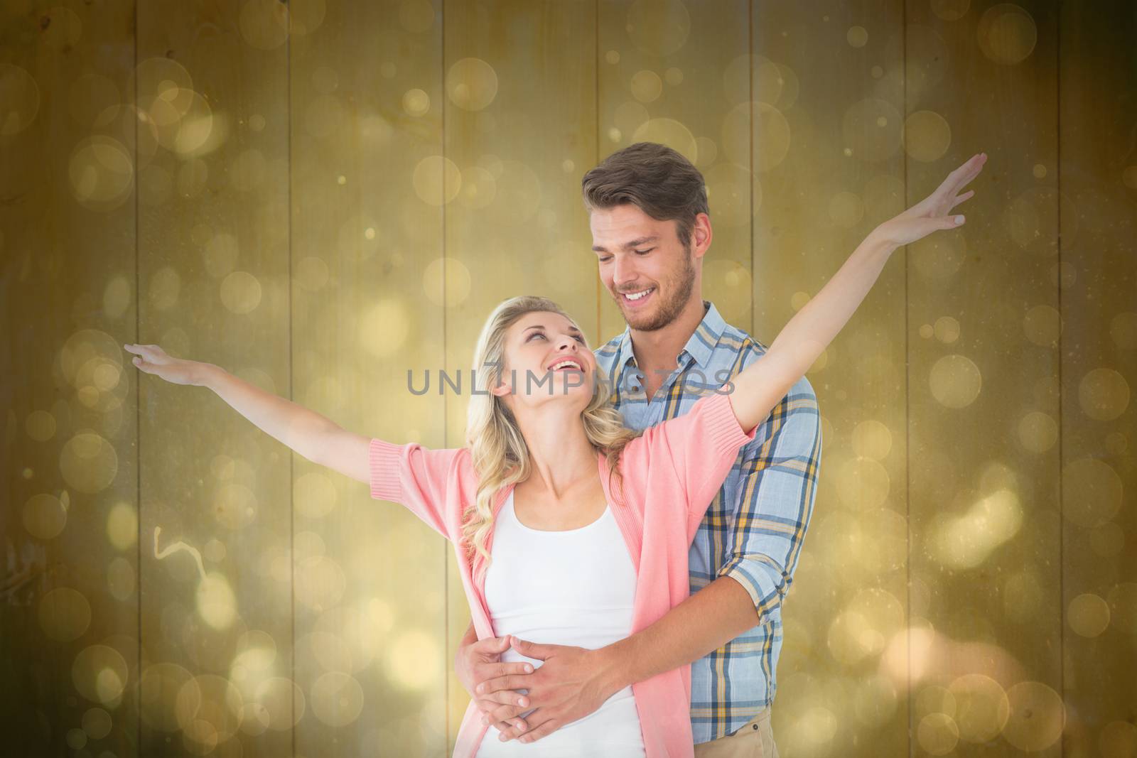 Attractive young couple smiling and embracing against black abstract light spot design