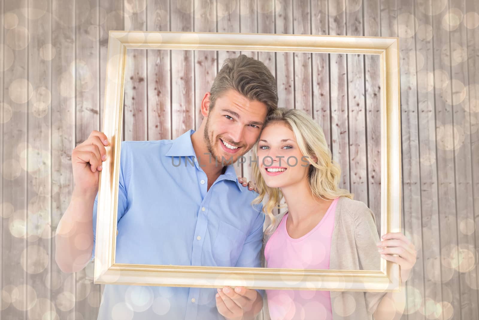Attractive young couple holding picture frame against light glowing dots design pattern