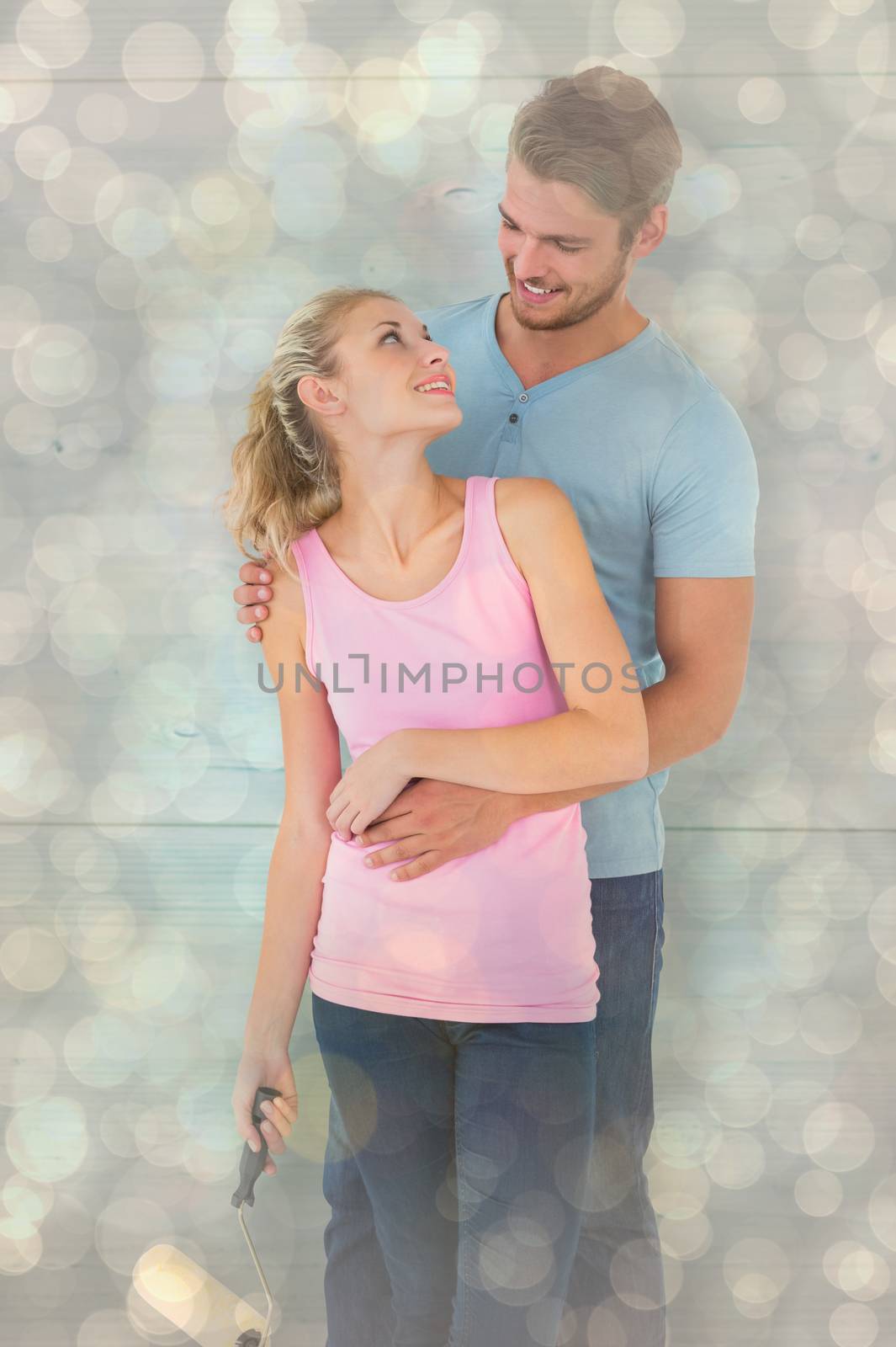 Young couple painting with roller against light glowing dots design pattern