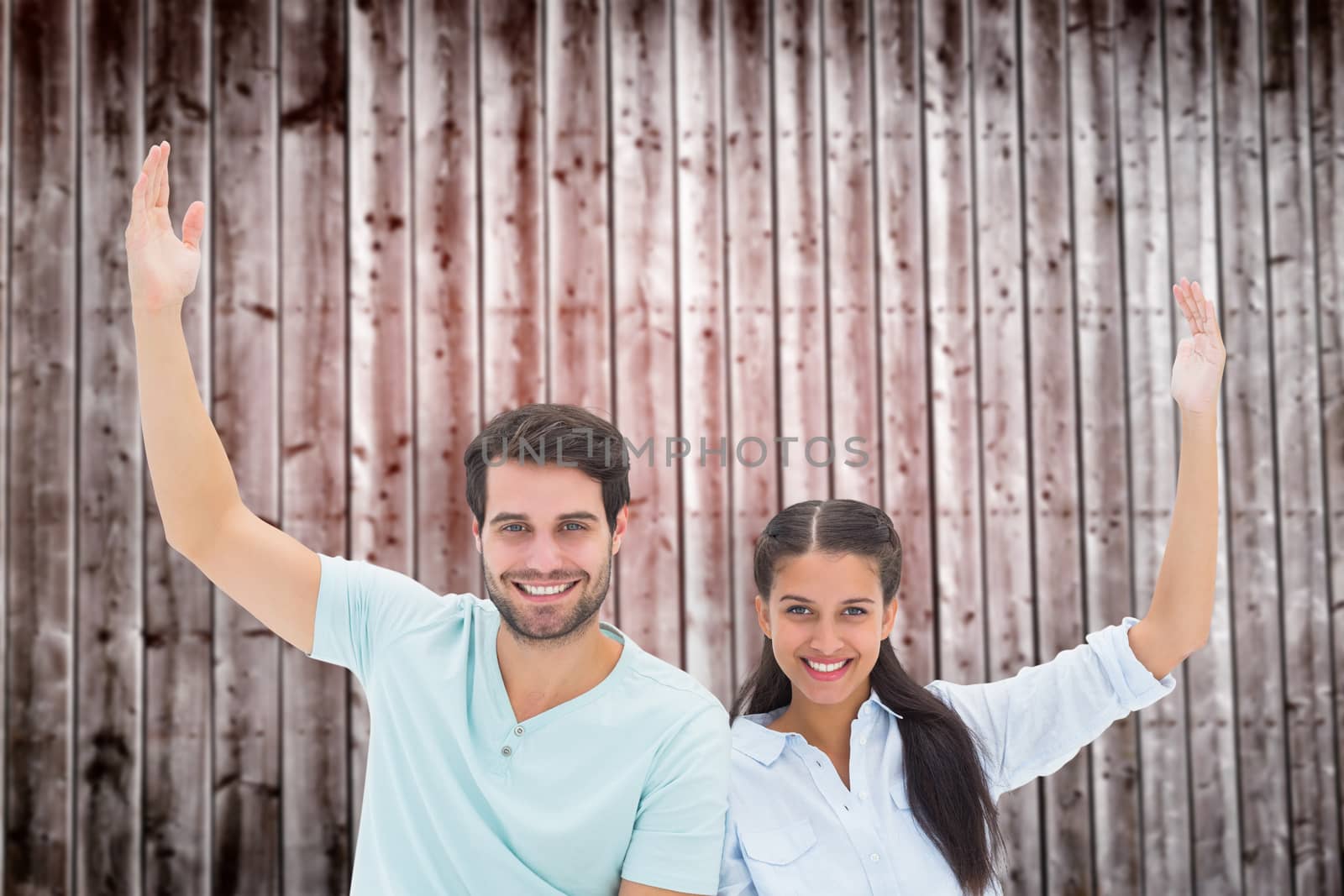Cute couple sitting with arms raised against wooden planks