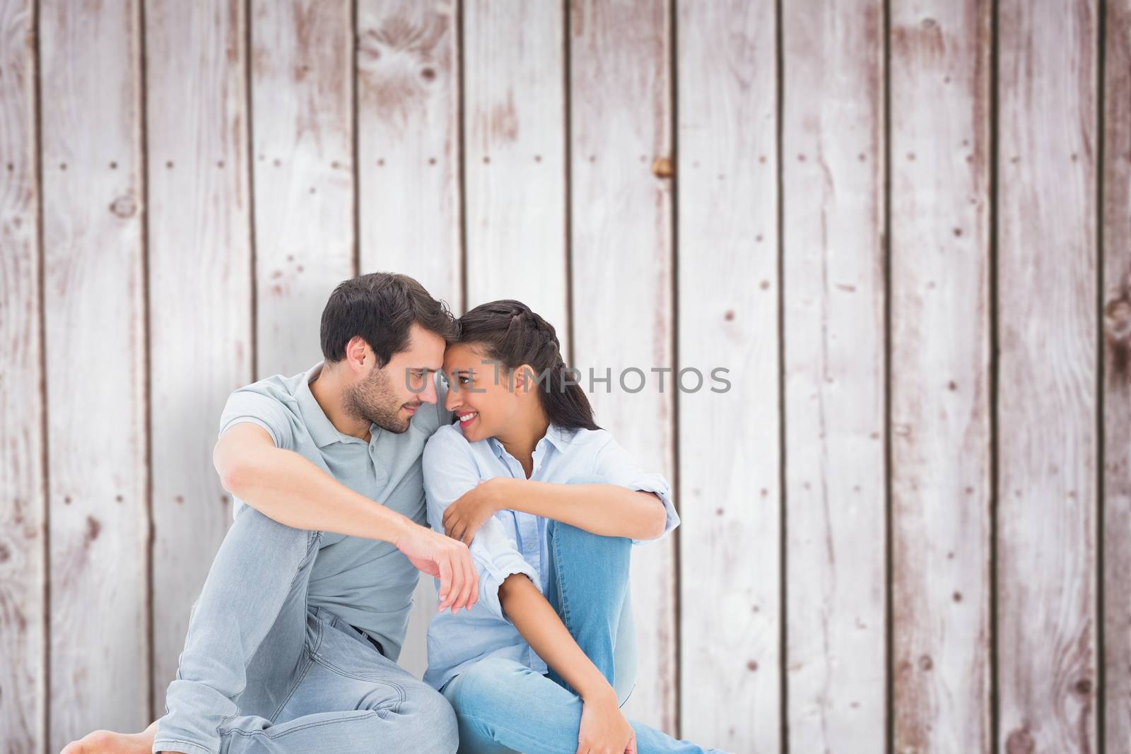 Cute couple sitting close together against wooden planks