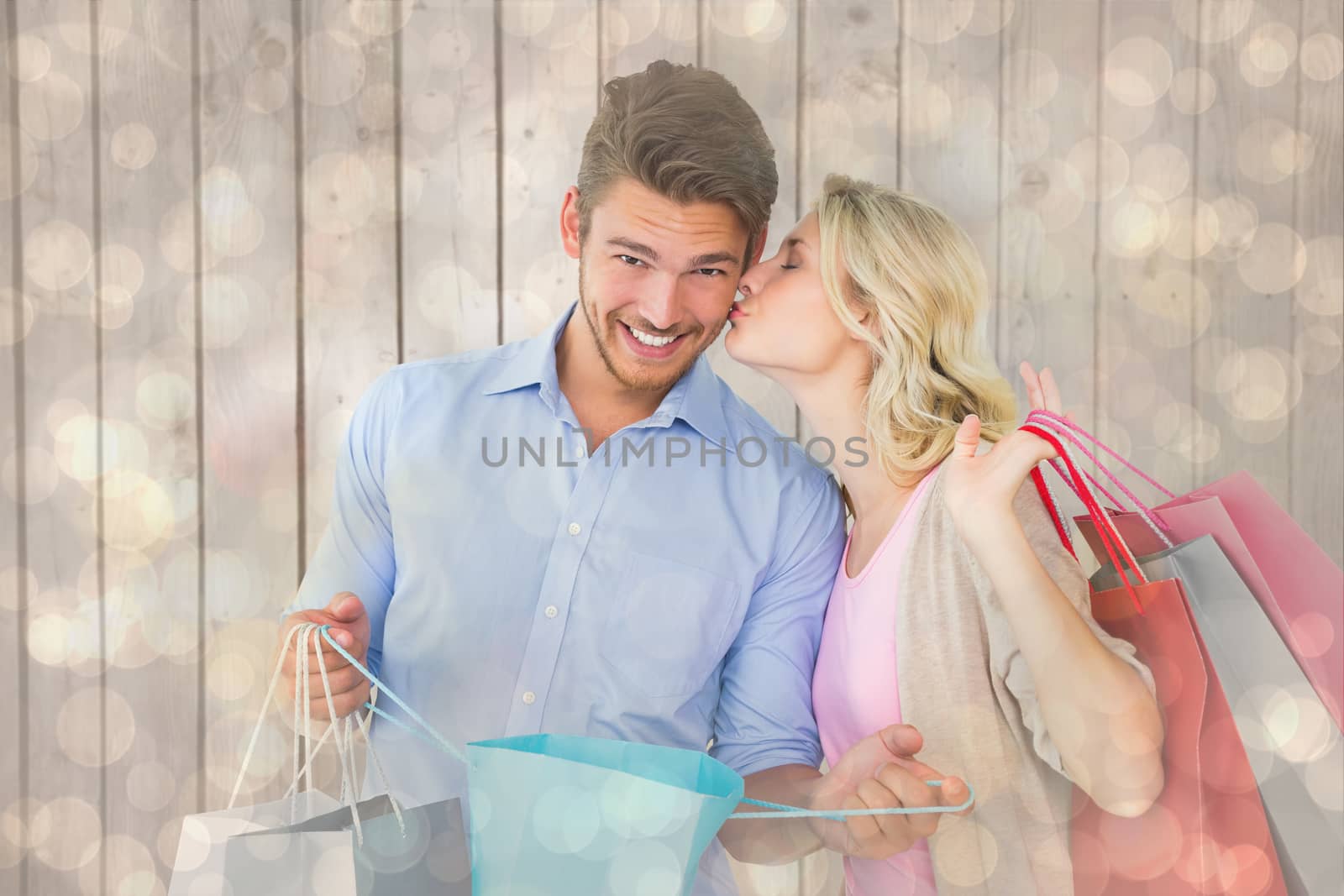 Attractive young couple holding shopping bags against light glowing dots design pattern