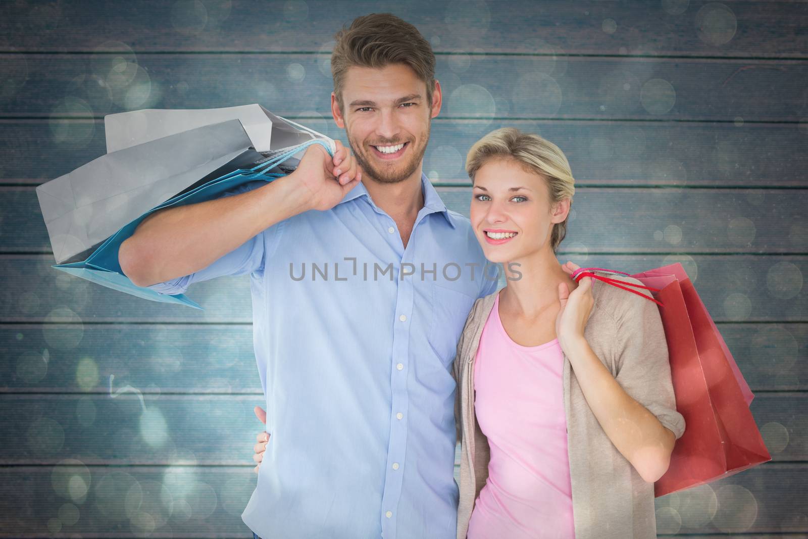 Attractive young couple holding shopping bags against black abstract light spot design