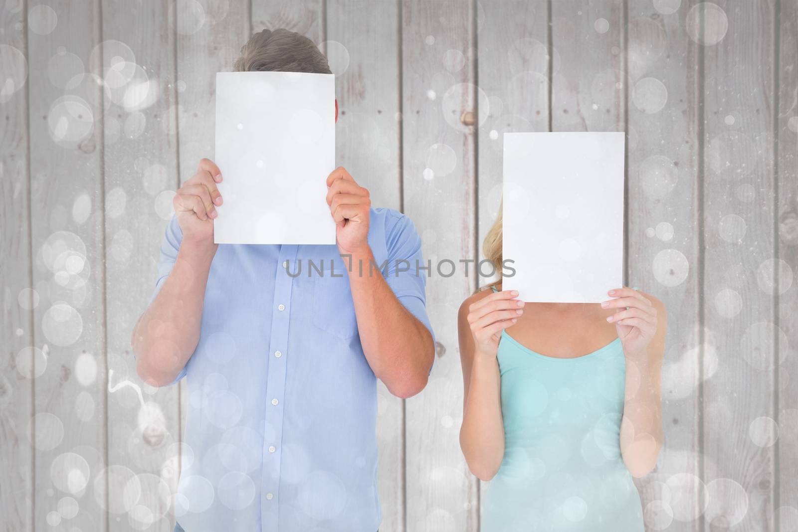 Composite image of young couple holding pages over their faces by Wavebreakmedia