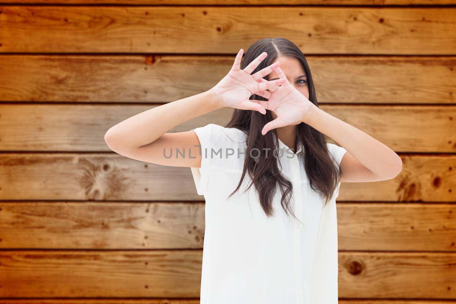 Fearful brunette covering her face against wooden planks background