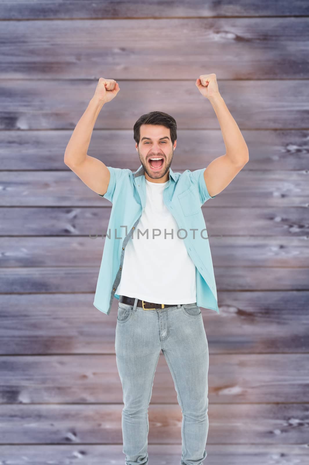 Happy casual man cheering at camera against faded grey wooden planks