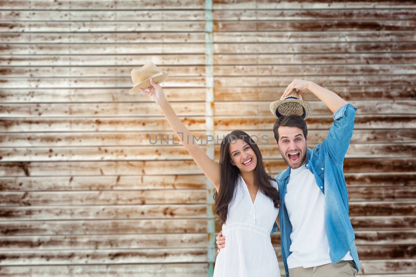 Happy hipster couple smiling at camera and cheering against wooden planks