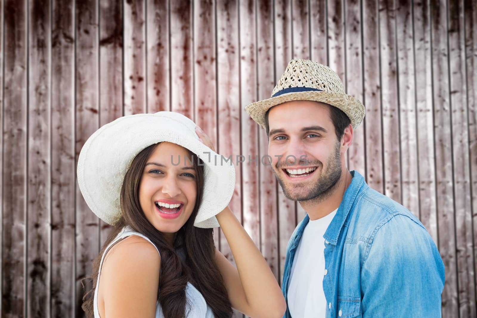 Happy hipster couple smiling at camera against wooden planks