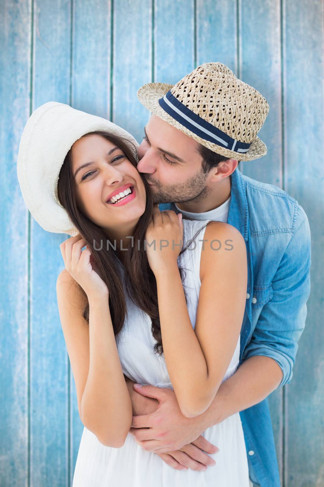 Happy hipster couple hugging and smiling against wooden planks