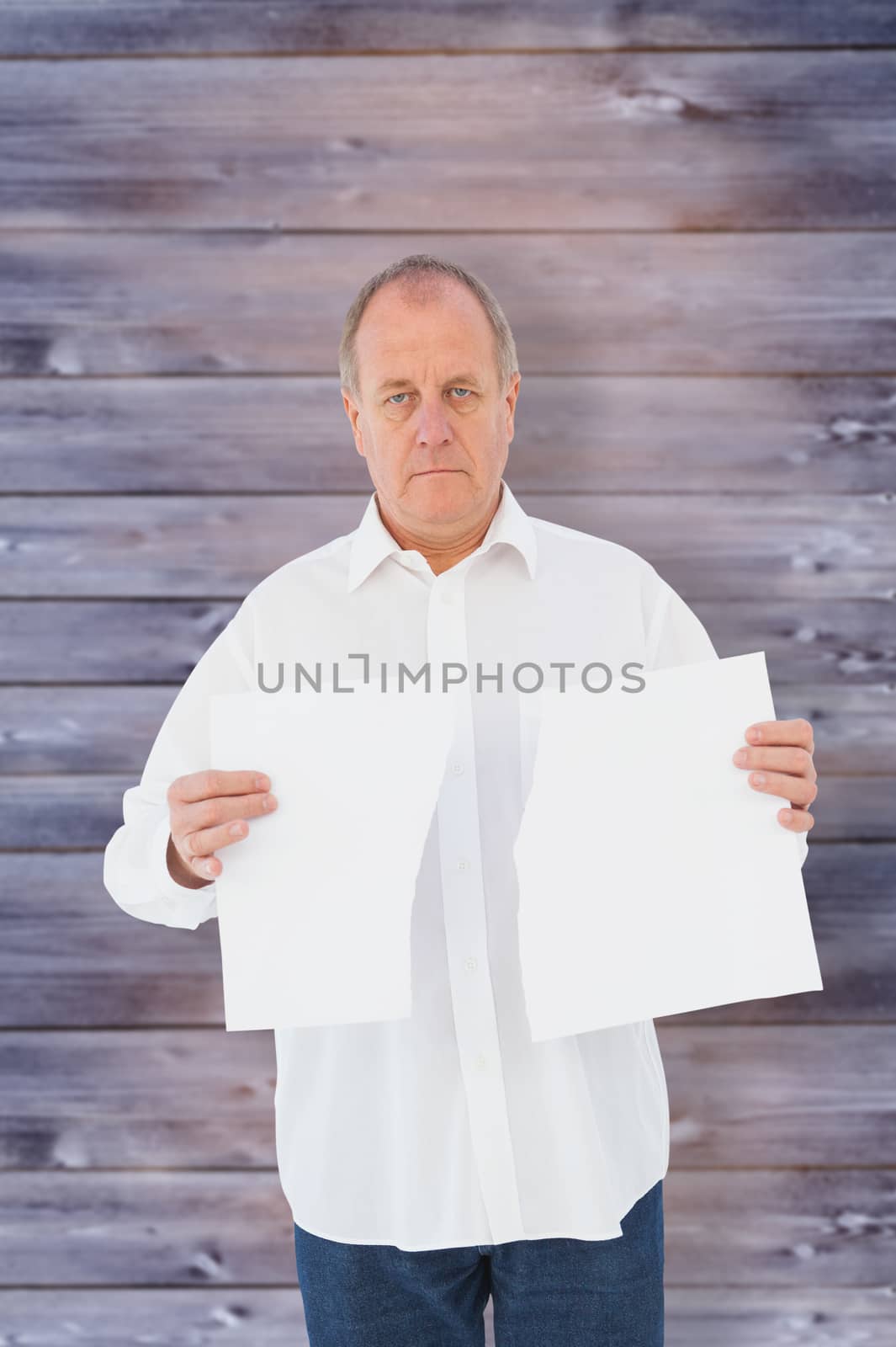 Serious man holding torn sheet of paper against faded grey wooden planks