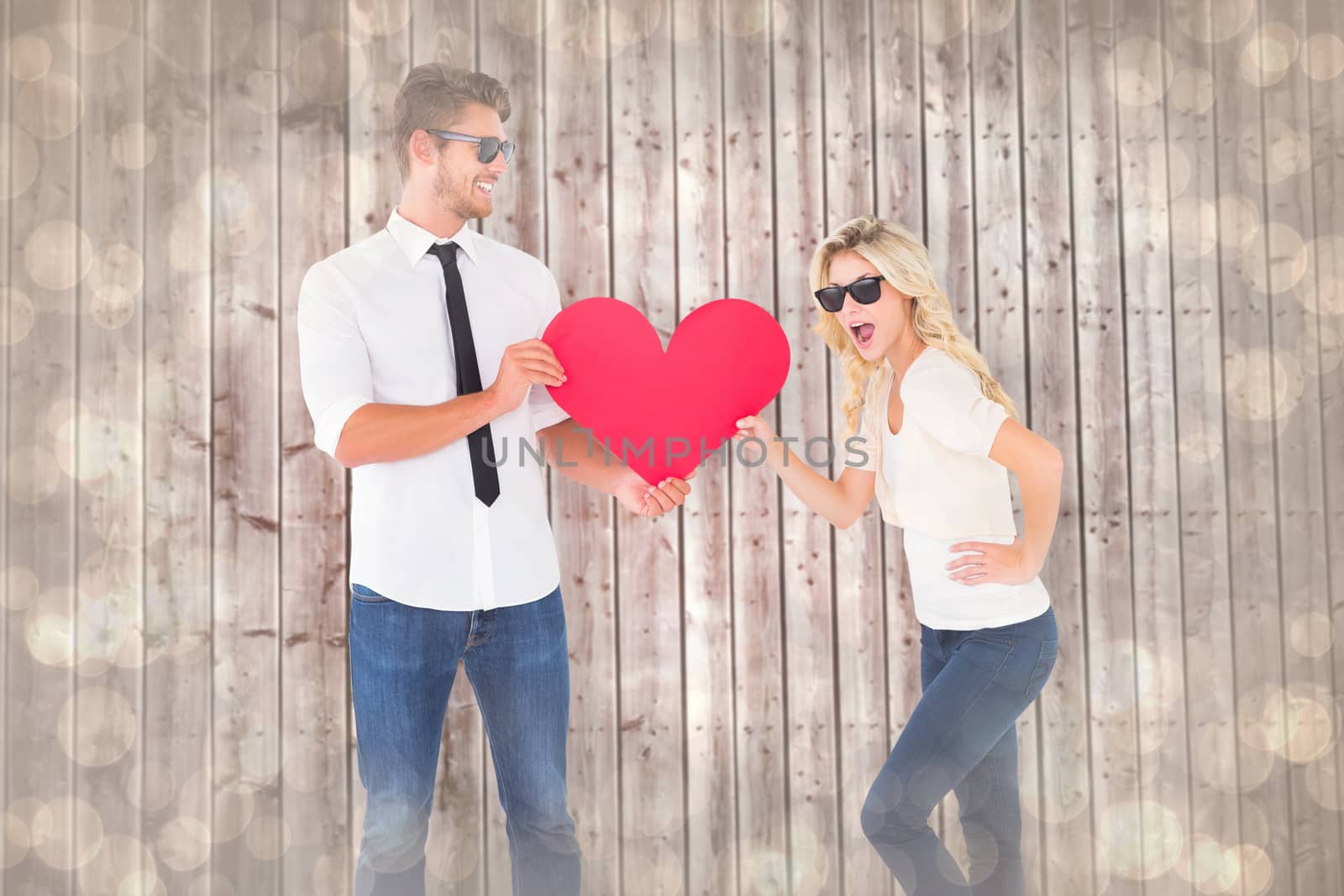 Cool young couple holding red heart against light glowing dots design pattern