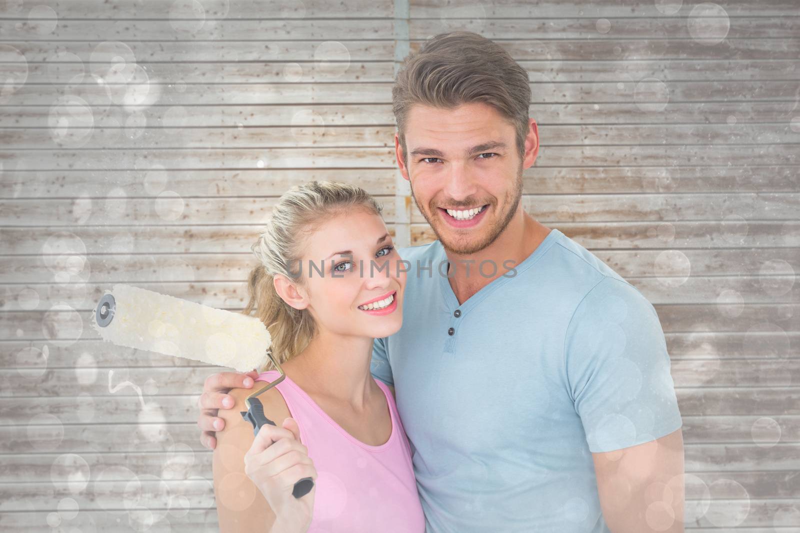 Composite image of young couple hugging and holding paint roller by Wavebreakmedia